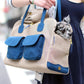 Small dog being carried in a Canine Styles beige and turquoise dog carrier over the shoulder pet purse.