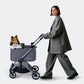 Woman pushing a roomy and stylish Ibiyaya Maxi pet stroller with a dog inside.