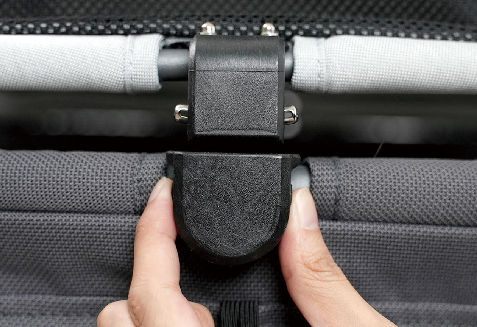 Close-up of a hand adjusting the clip on the canopy of the Ibiyaya Maxi pet stroller
