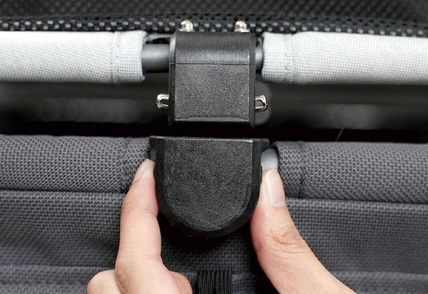 Close-up of a hand adjusting the clip on the canopy of the Ibiyaya Maxi pet stroller